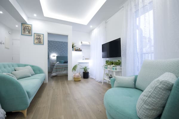 Reforma integral de apartamento, sala iluminada con sofas azul turquesa. Qbra y gestión de gremios ejecutada por reformas Urgull