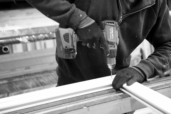 Trabajador carpinteria metálica probando mecanismo de apertura ventana aluminio. Reformas Urgull