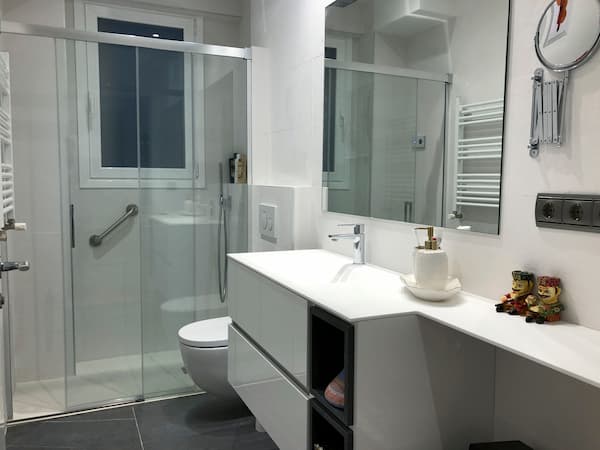 Reforma de baño con mueble de cuarto de baño blanco y encimera en solid surface.